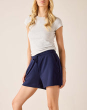 Load image into Gallery viewer, woman standing wearing Mersea Frenchie Pajamas Shorts in blue paired with a light gray top with her hands in the short pockets
