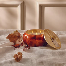 Load image into Gallery viewer, lit orange pumpkin shaped candle with a gold lid
